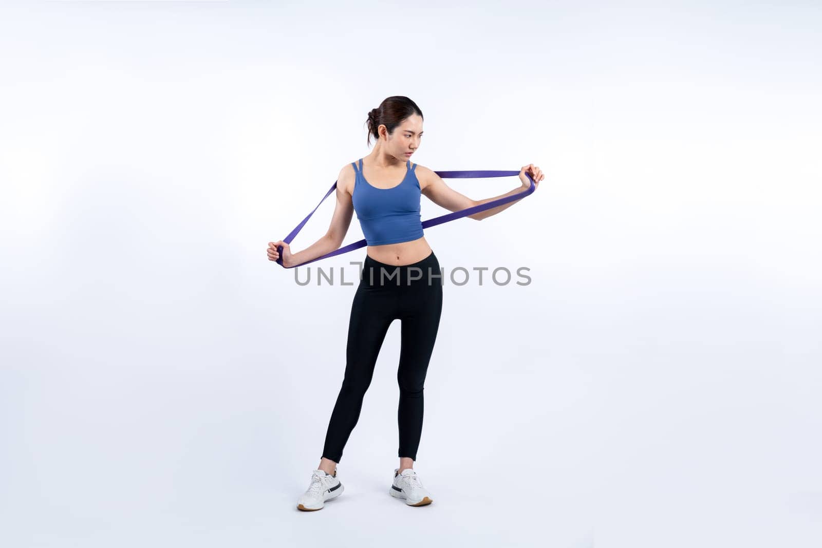 Vigorous energetic woman in sportswear portrait stretching resistance band. by biancoblue