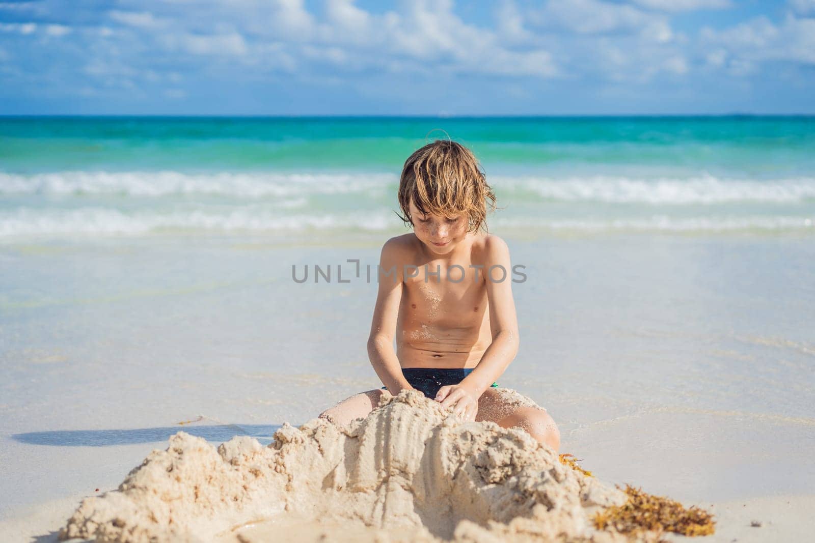 Young boy's pure delight as he explores the sandy playground of the beach, shaping dreams with grains of sand.