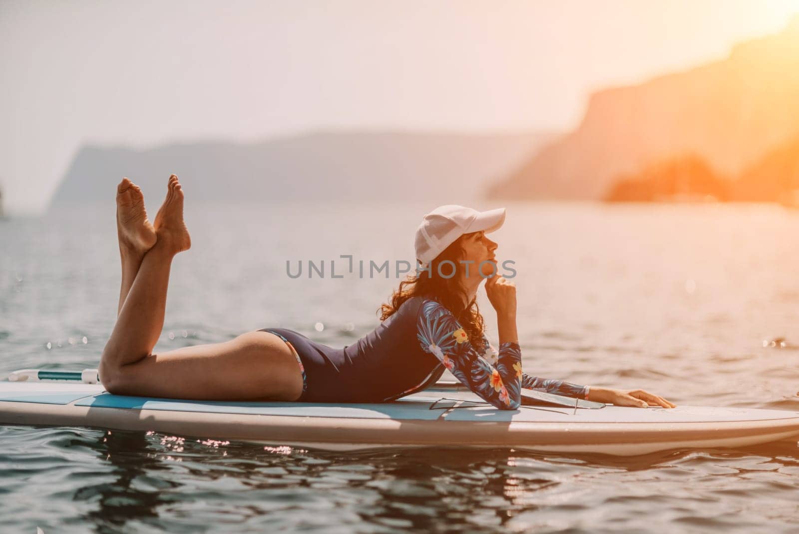 Woman sup yoga. Middle age sporty woman practising yoga pilates on paddle sup surfboard. Female stretching doing workout on sea water. Modern individual hipster outdoor summer sport activity