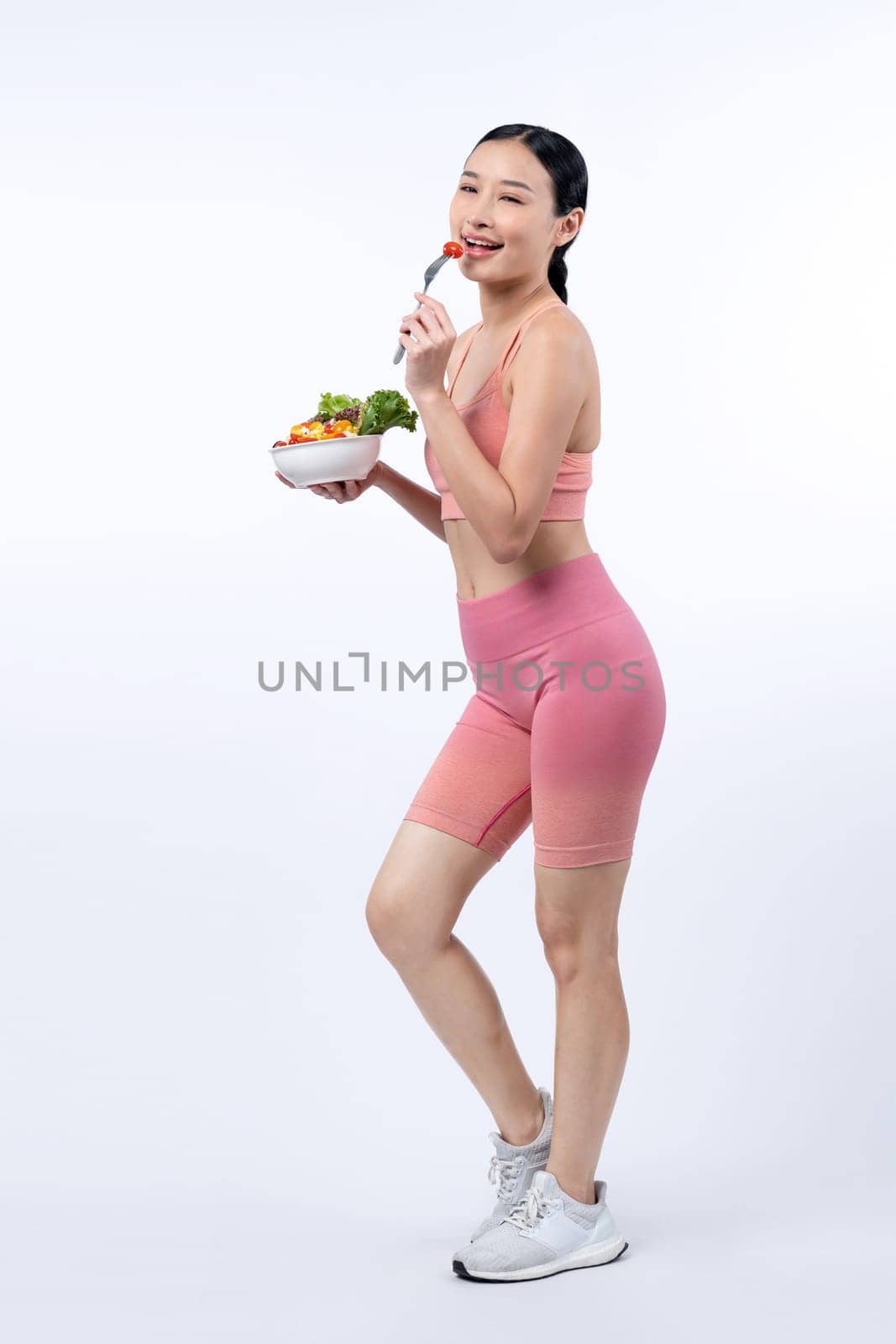 Asian woman in sportswear holding salad bowl on isolated background. Vigorous by biancoblue