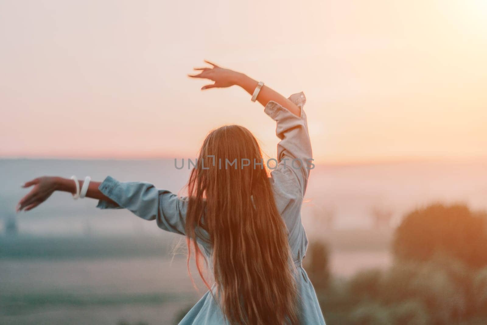 Romantic beautiful bride in white dress posing with sea and mountains in background. Stylish bride standing back on beautiful landscape of sea and mountains on sunset