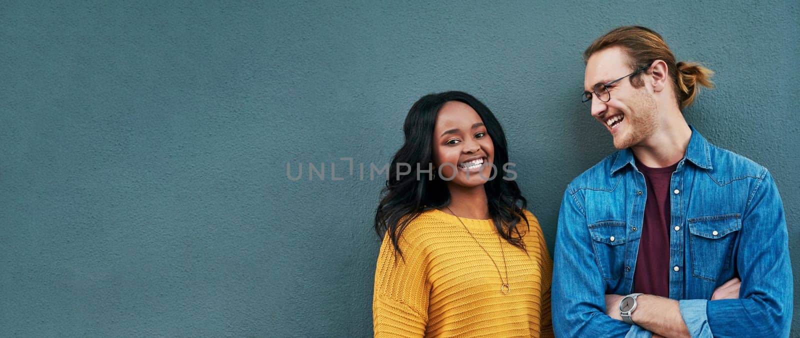 Happy, conversation and couple by wall with mockup space for advertising, promotion or marketing. Smile, talking and young interracial man and woman in discussion together by gray background mock up