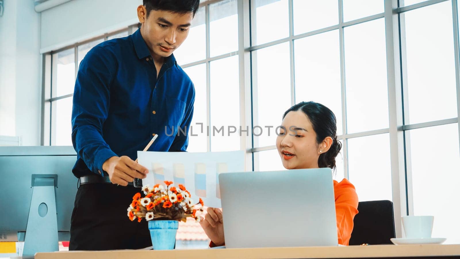 Two business people talk project strategy at office meeting room. Businessman discuss project planning with colleague at modern workplace while having conversation and advice on financial report. Jivy