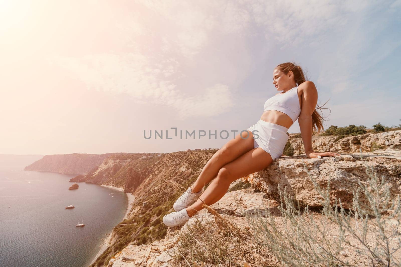 Middle aged well looking woman with black hair doing Pilates with the ring on the yoga mat near the sea on the pebble beach. Female fitness yoga concept. Healthy lifestyle, harmony and meditation.