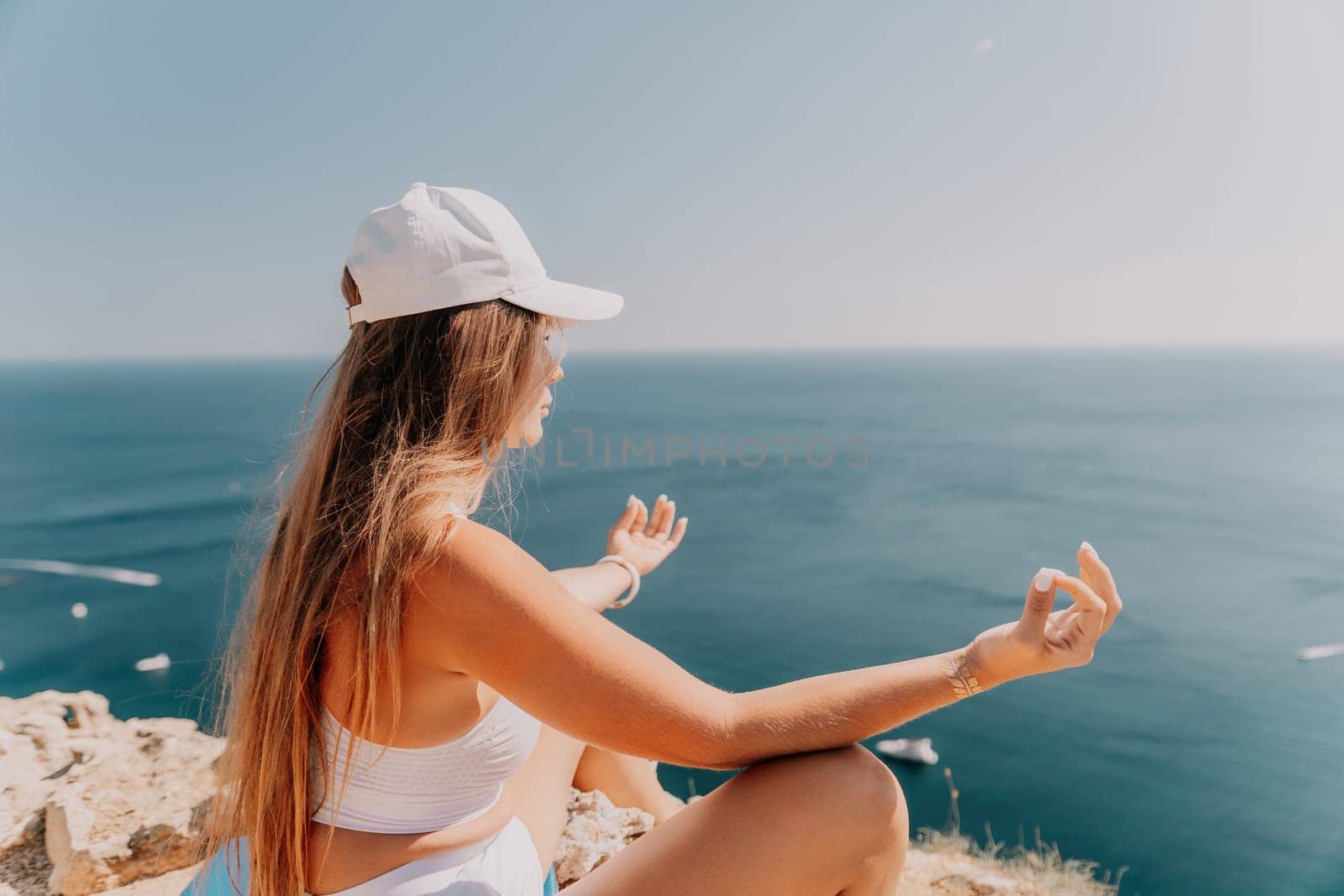 Woman meditating in yoga pose silhouette at the ocean, beach and rock mountains. Motivation and inspirational fit and exercising. Healthy lifestyle outdoors in nature, fitness concept.