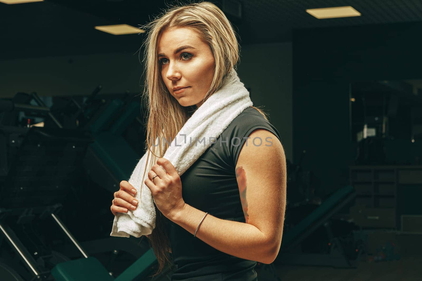 Young woman with towel sitting and resting in a gym