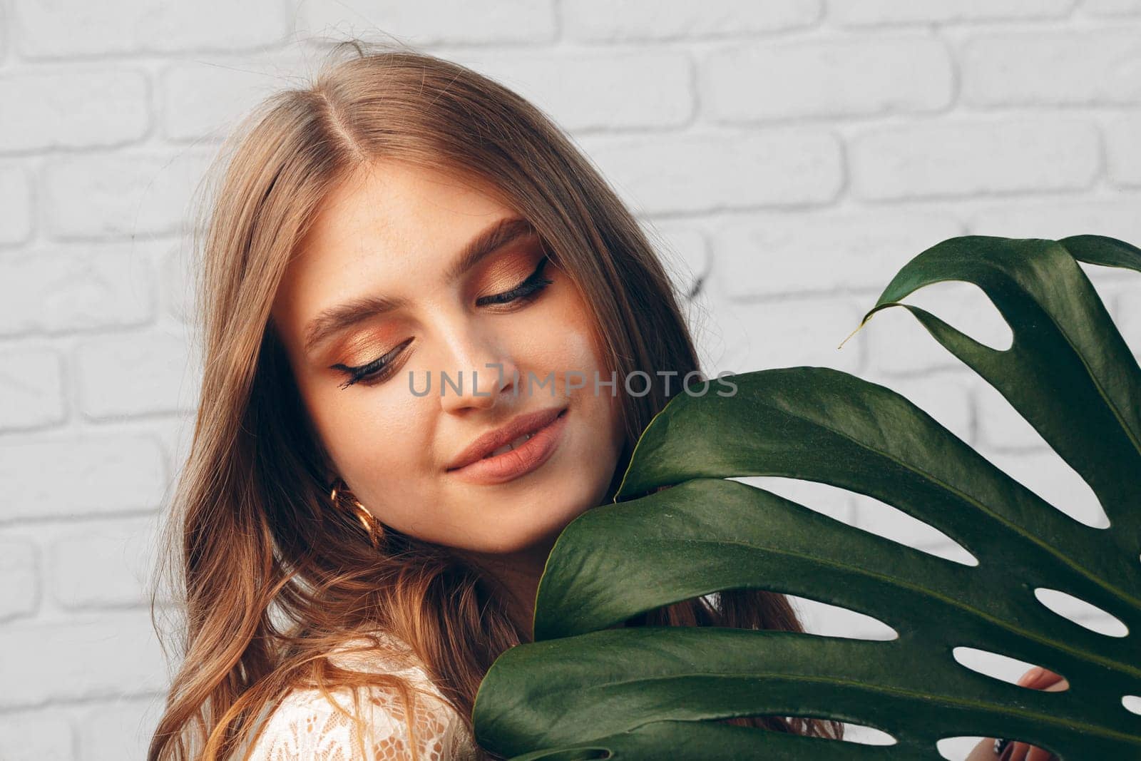 Portrait of a beautiful woman with monstera leaves. Creative photo