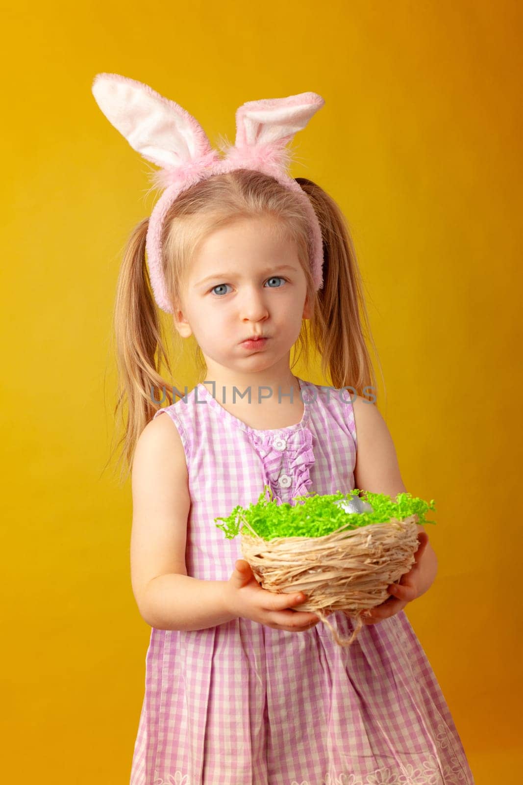 Little girl holding basket with colored eggs. Easter concept