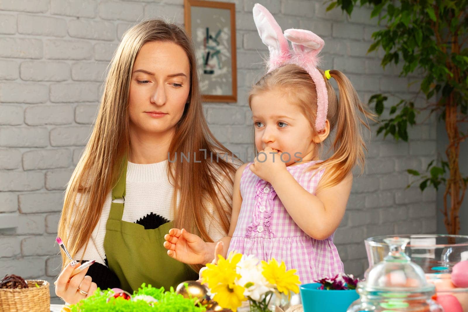 Little girl and her mother coloring eggs for Easter together