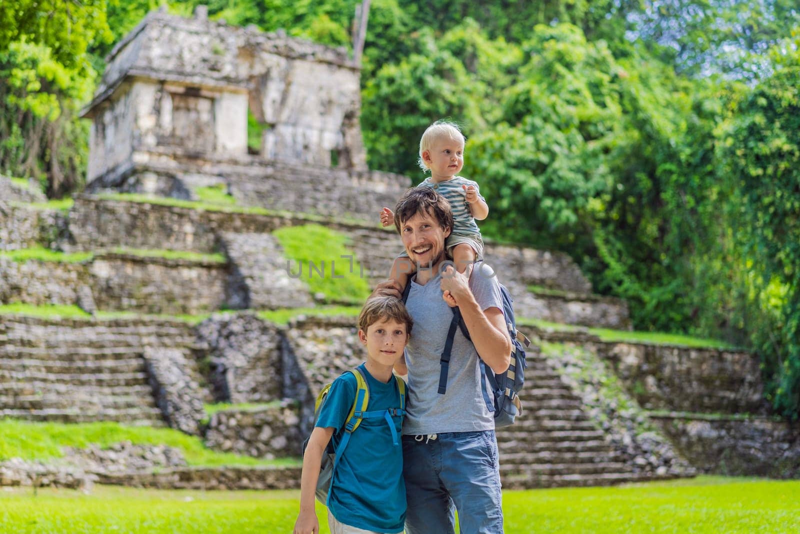 Mother with his toddler and teenage sons exploring the ancient pyramids of Palenque, Mexico, surrounded by dense jungle. Cultural heritage and adventure travel concept.