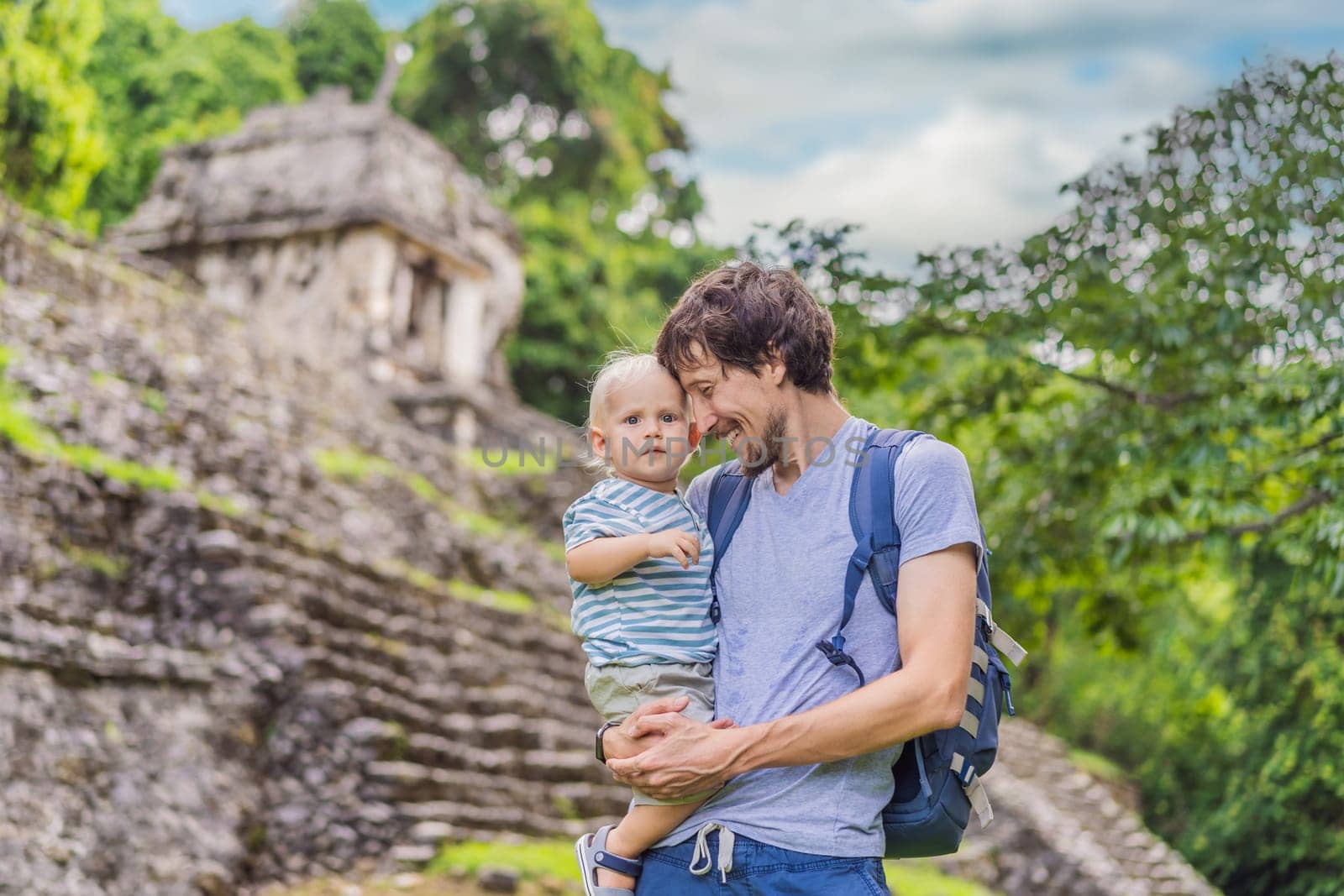 Mother with his toddler son exploring the ancient pyramids of Palenque, Mexico, surrounded by dense jungle. Cultural heritage and adventure travel concept.