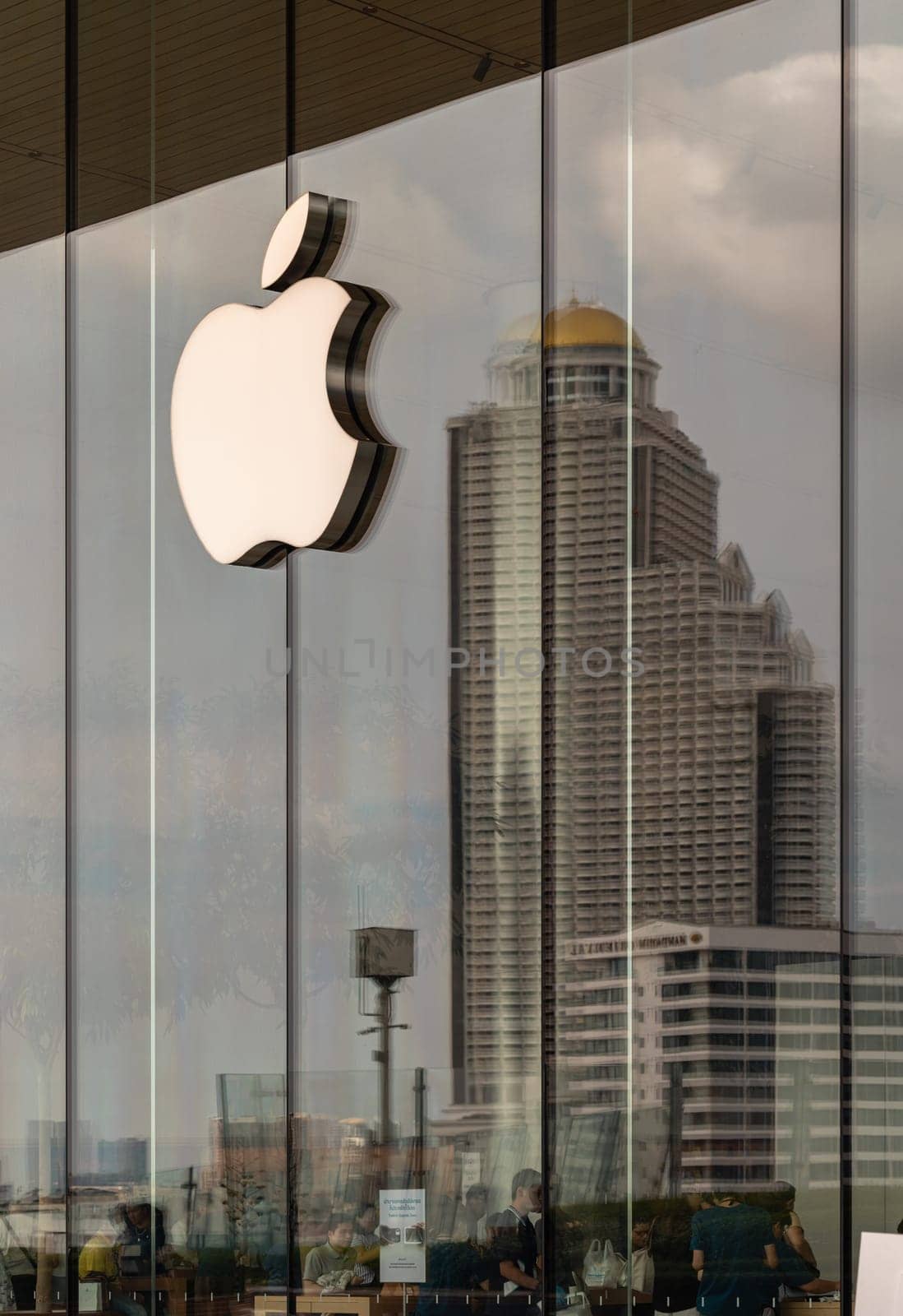 Bangkok, Thailand - 28 Sep, 2024 - Modern stylish logo sign attach to glass wall with reflections of high building at Apple store in Iconsiam luxury shopping mall. Copy space Selective focus.