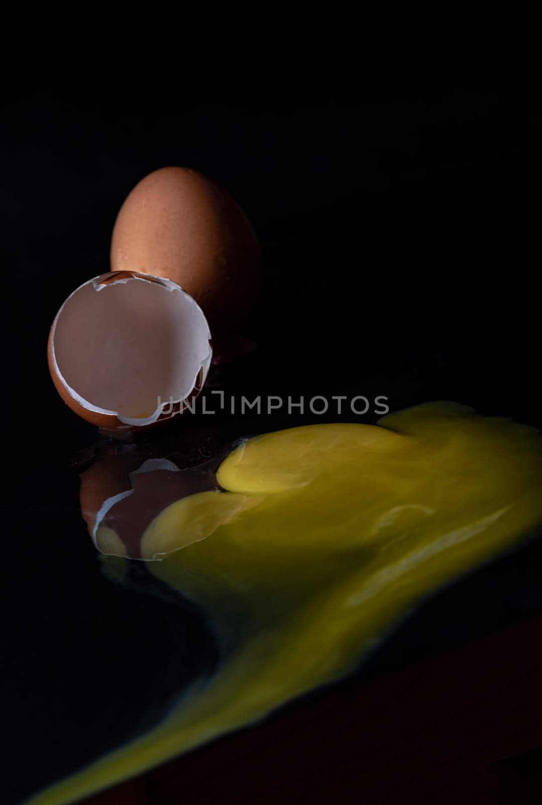 View of Broken egg yolk with Broken raw chicken eggshell in front of Fresh chicken egg (Hen eggs) on Dark background. Fresh eggs from the farmer, Natural organic healthy food concept, Space for text, Selective focus.