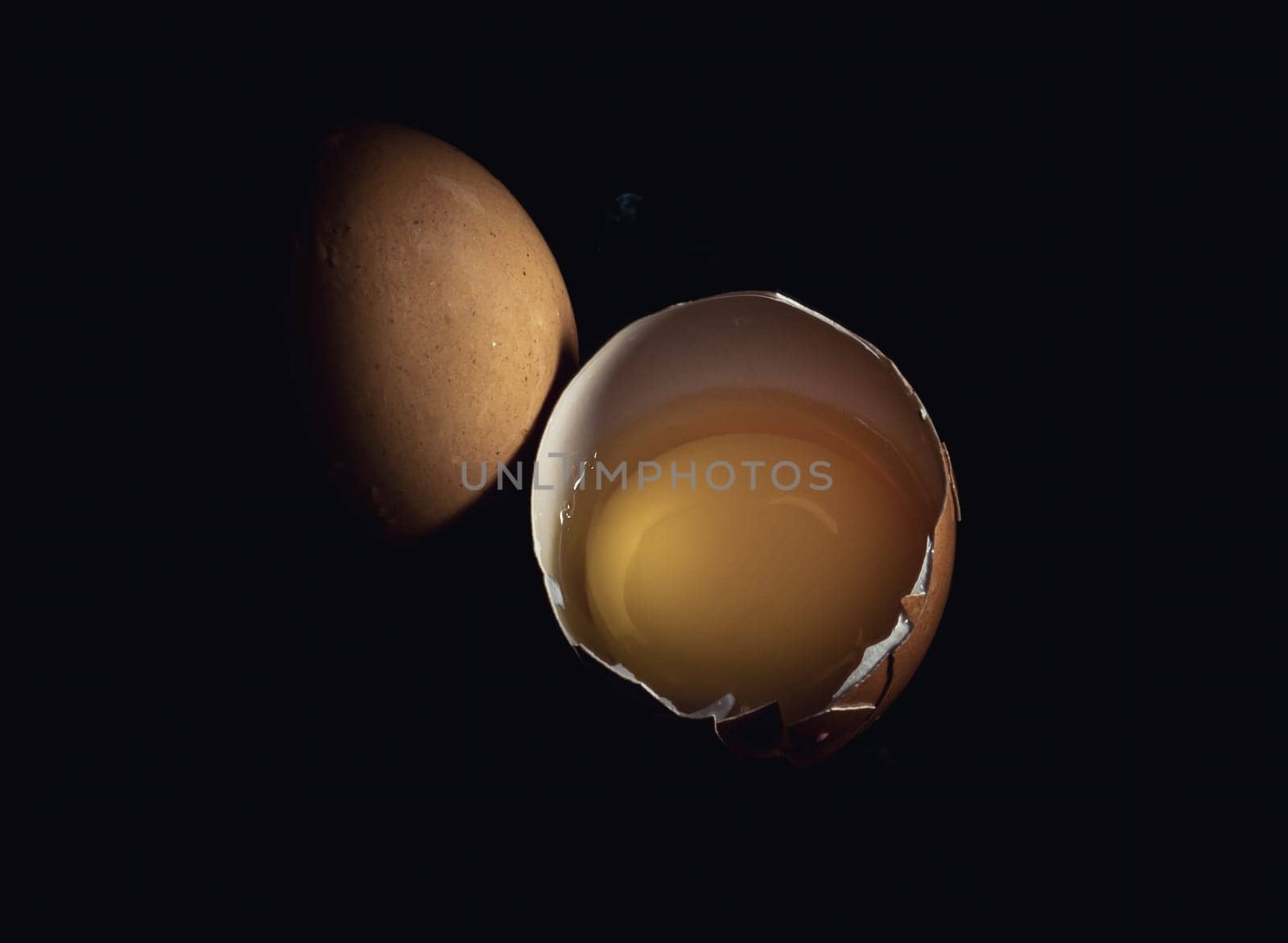 Top view of Egg yolk in Broken raw chicken eggshell and Fresh chicken egg (Hen egg) on Black background. Fresh eggs from the farmer, Natural organic healthy food concept, Copy space, Selective focus.