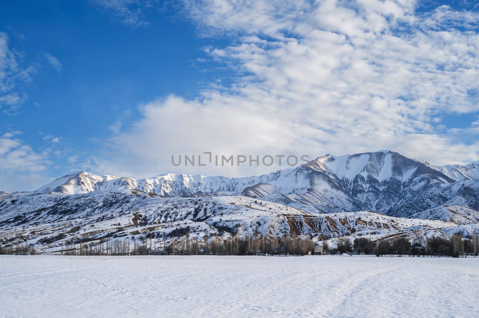 winter landscape with the Tien Shan mountains in Kazakhstan in snow under a blue sky with clouds