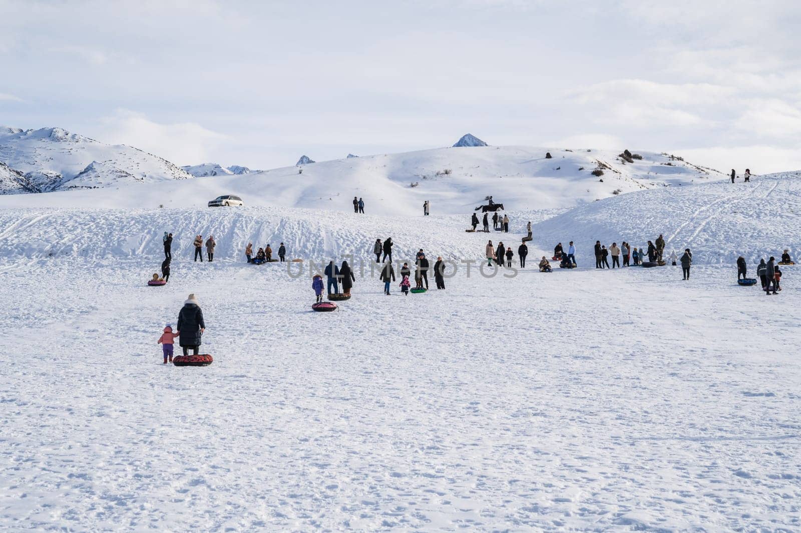 People relax in nature and ride downhill on tubing during the winter holidays. Shymkent, Kazakhstan - January 27, 2024