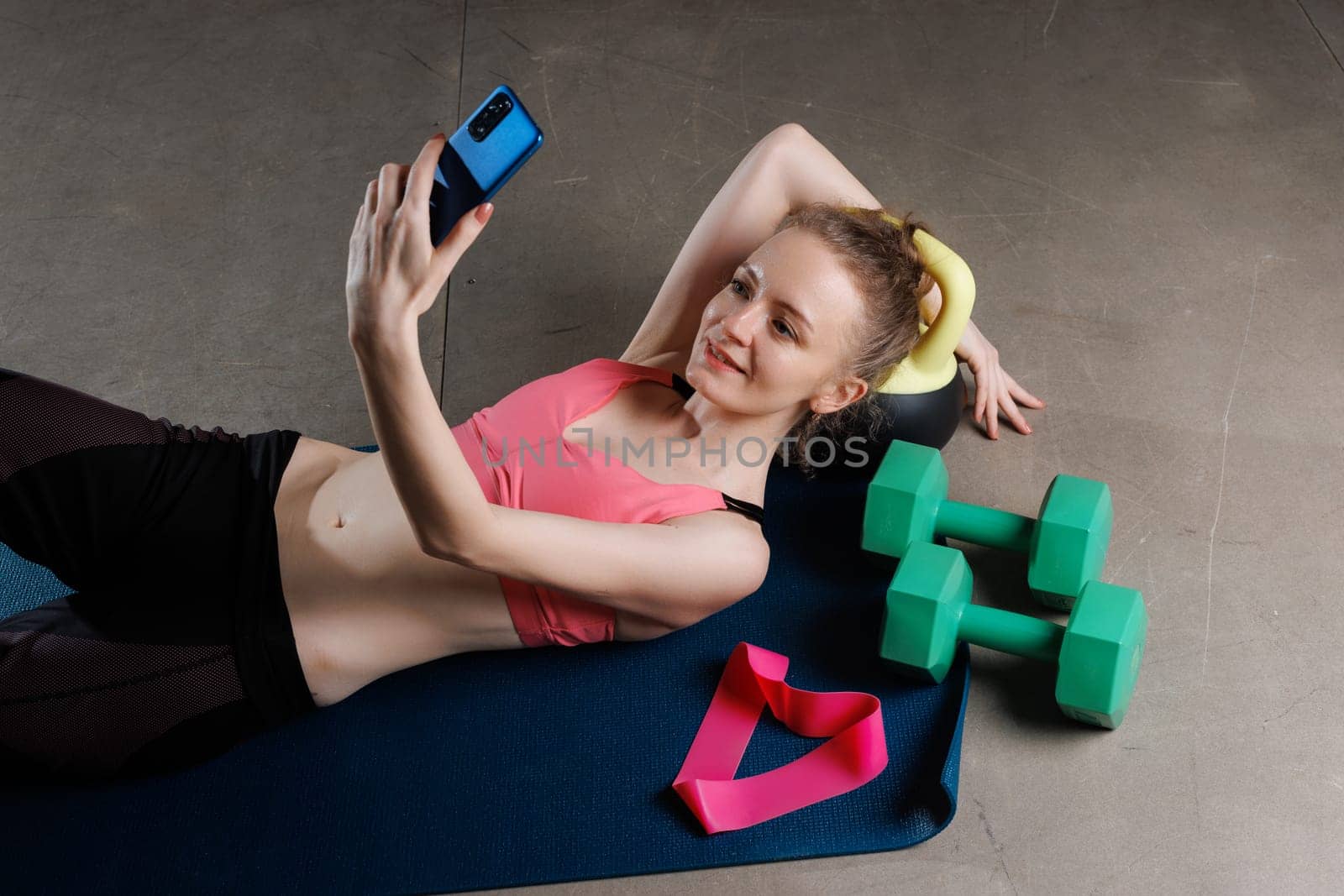 girl leads online training with rubber loops lying on her back, concept of doing sports, expander fitness rubber band in the shape of a heart