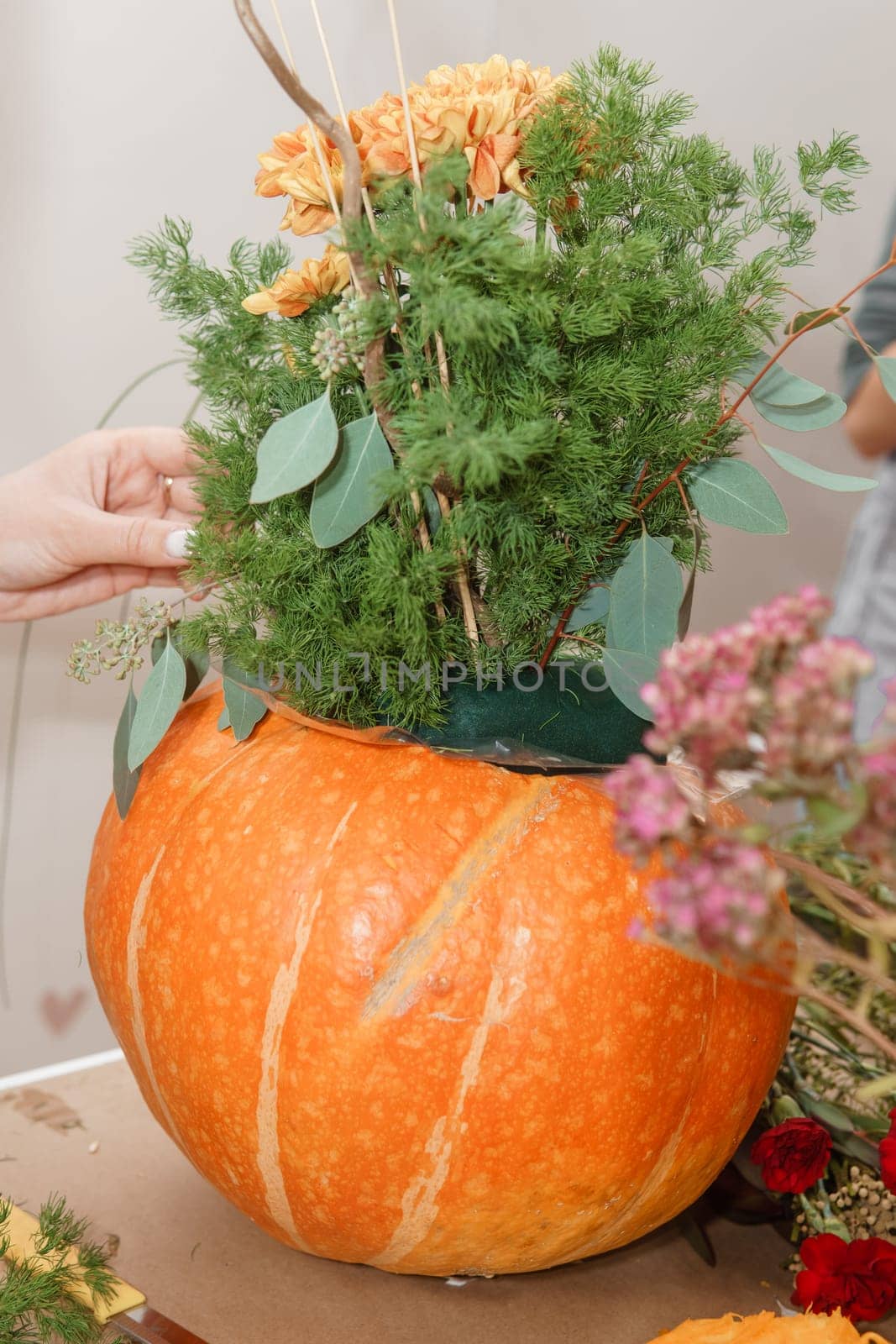 Flower arrangement in a pumpkin, autumn interior decor. Creating handmade autumn decor