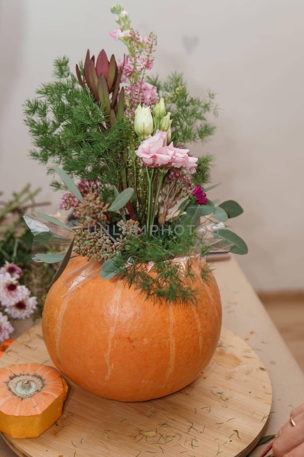 Flower arrangement in a pumpkin, autumn interior decor. Creating handmade autumn decor