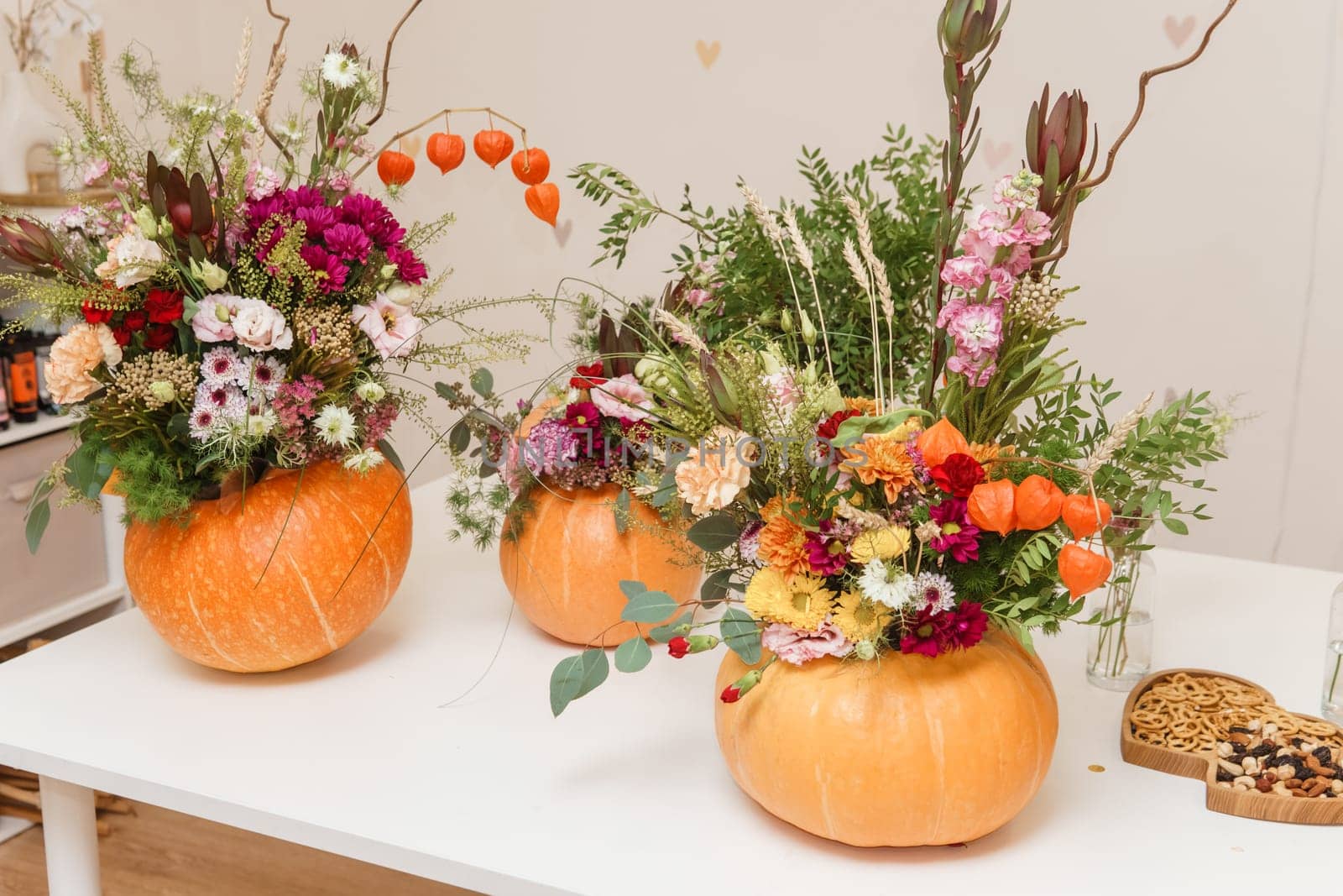 Flower arrangement in a pumpkin, autumn interior decor. Creating handmade autumn decor