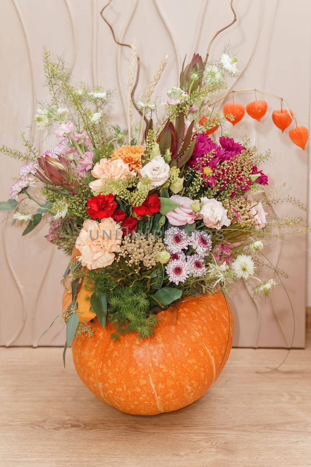 Flower arrangement in a pumpkin, autumn interior decor. Creating handmade autumn decor