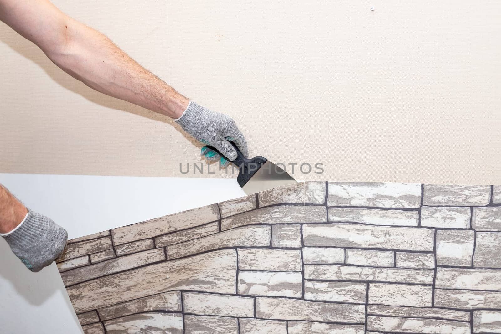 woman tears off Wallpaper, removing Wallpaper from the wall with a spatula, the process of updating the wall room repair.