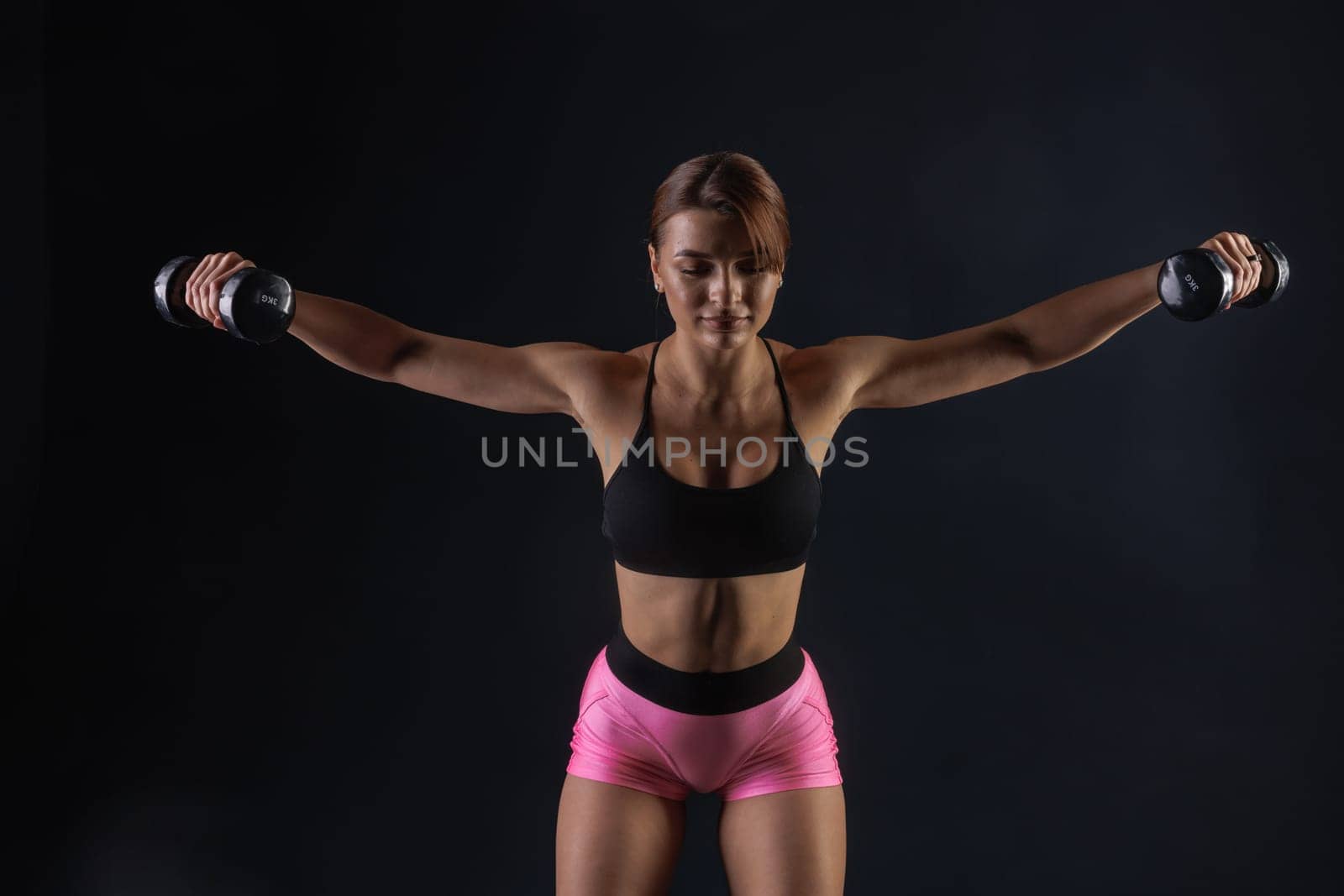 sporty girl doing exercises with dumbbells on black background, sport concept, healthy and beautiful body