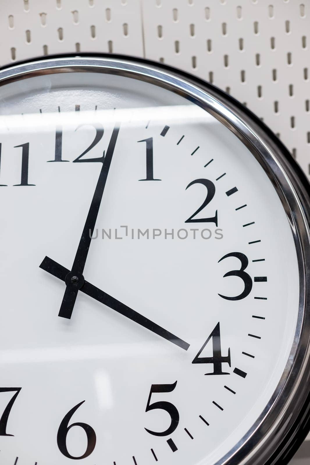 Simple modern wall clock in silver color frame, isolated on white background