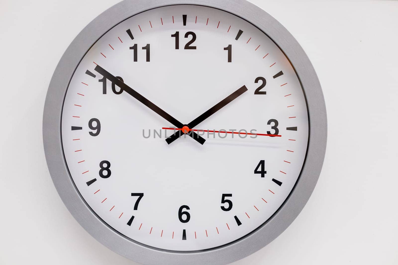 Simple modern wall clock in silver color frame, isolated on white background