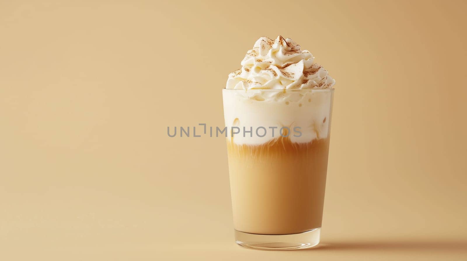 A refreshing glass of iced coffee layered with creamy whipped topping and sprinkled with spices, set against a soft beige background, makes for an enticing beverage choice.