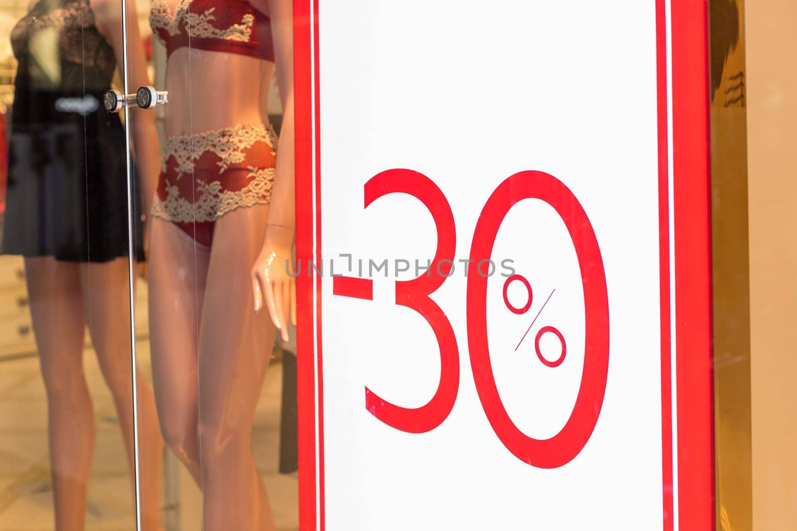 Discount percentage sign display in fashion department store during sale season period.