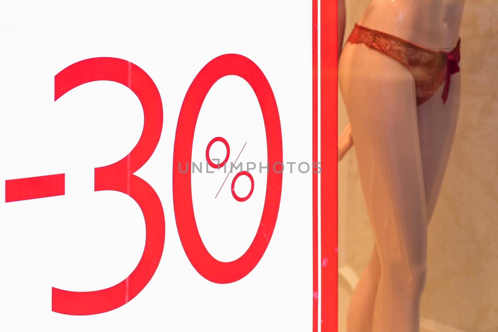 Discount percentage sign display in fashion department store during sale season period.