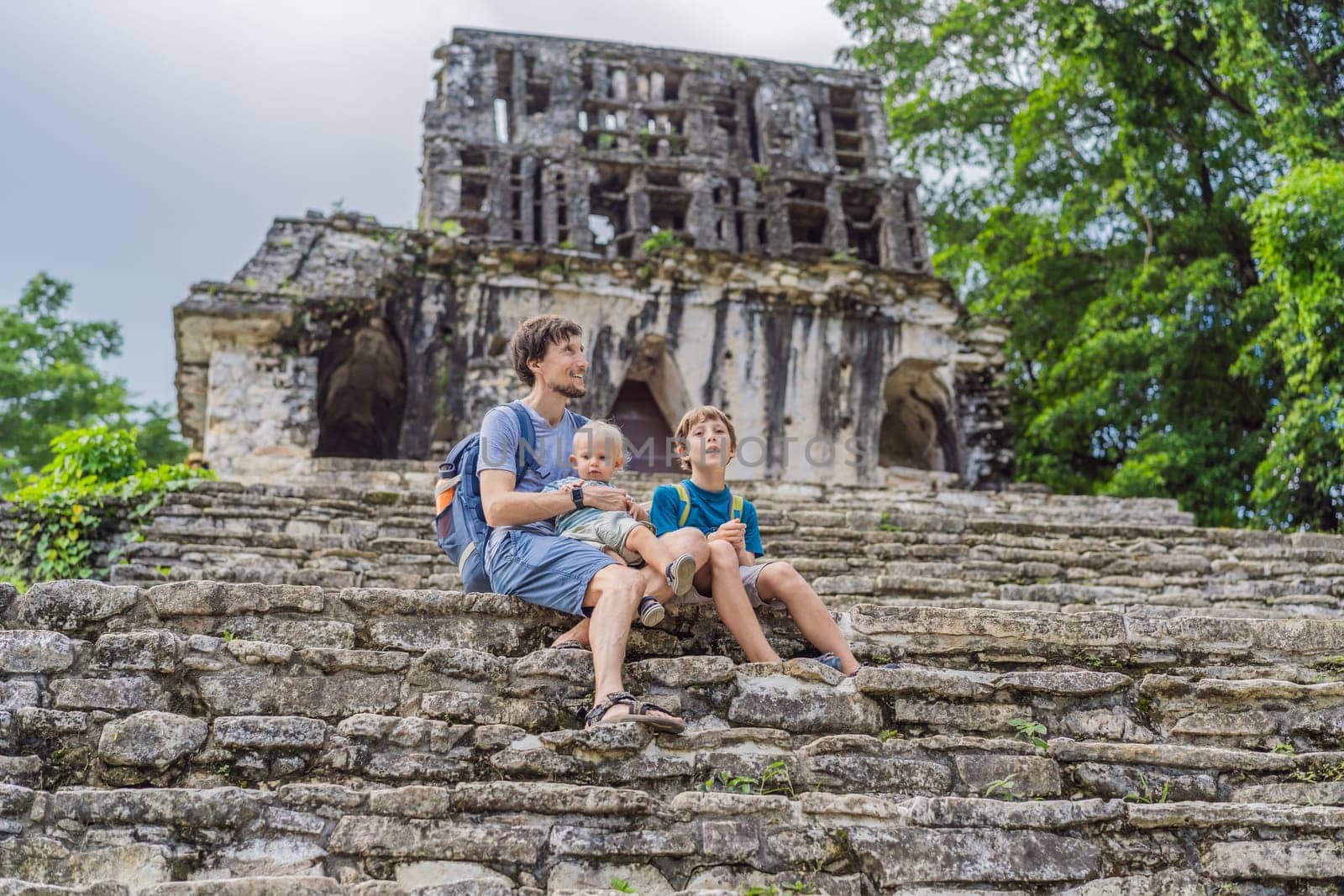 Father with his toddler and teenage sons exploring the ancient pyramids of Palenque, Mexico, surrounded by dense jungle. Cultural heritage and adventure travel concept.