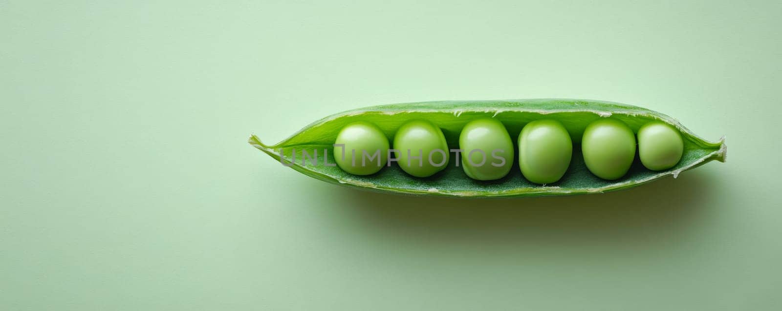 Close-up of fresh green peas in a pod against pastel green background. Nature and organic food concept.