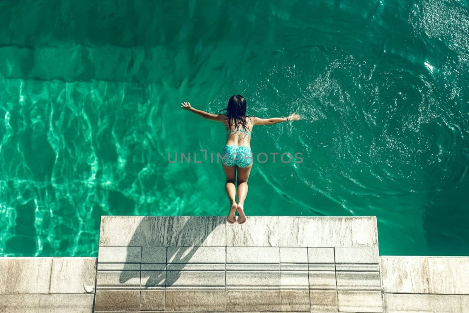 Young woman is taking a refreshing dip in the crystal clear turquoise water, her arms outstretched as she enjoys a moment of pure joy and freedom