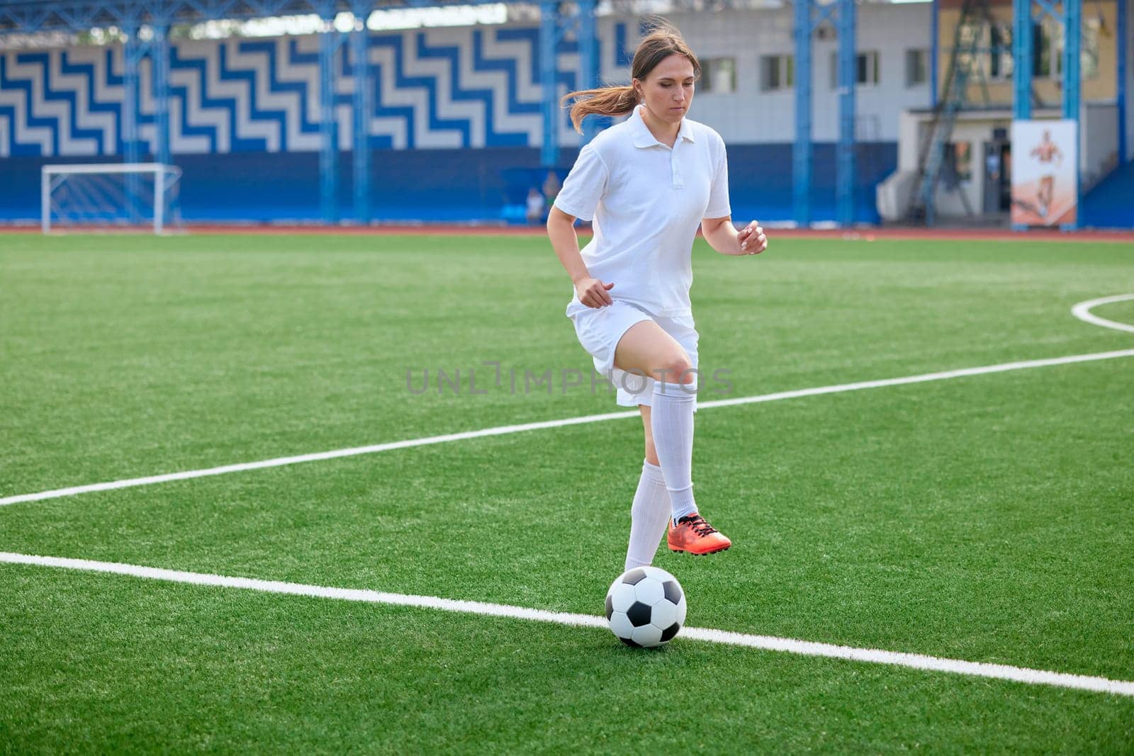 And the soccer player in the uniform and red clothes controlling the soccer ball on the Green Field. football training