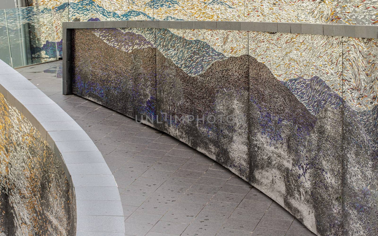 Bangkok, Thailand - 28 Sep, 2024 - A sloping walkway leading down to a park in a high-rise building with cladding in the shape of an arch are decorated with colorful Stained glass scraps mosaic.Space for text, Selective focus.