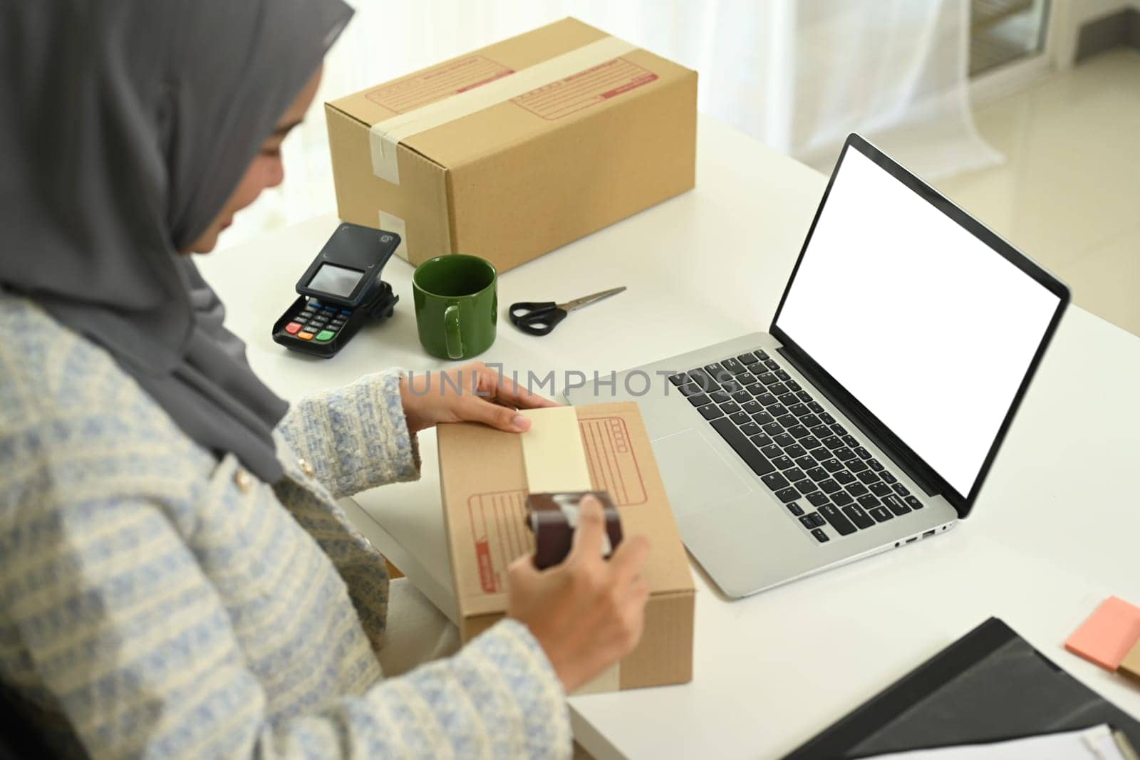 Smiling small business owner packaging a parcel for delivery to customers. E-commerce concept.