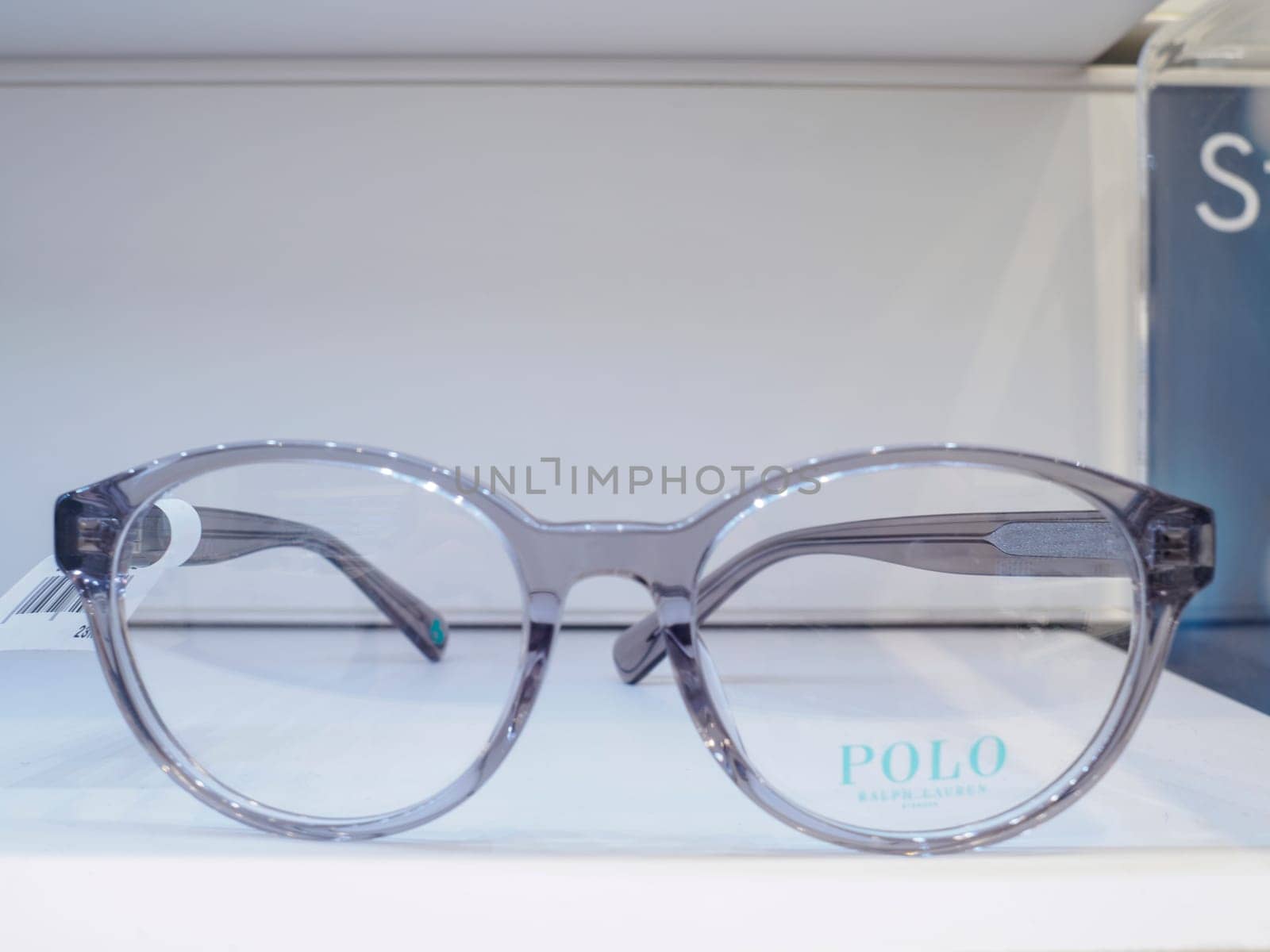 Pair of transparent eyeglasses with a thick grey frame is displayed on a white surface, showcasing their modern and stylish design