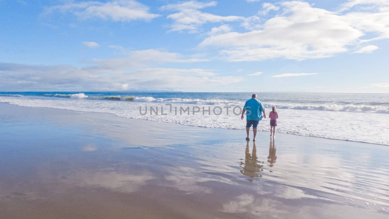 In California, a father and daughter share a serene winter walk along the deserted sands of El Capitan State Beach.