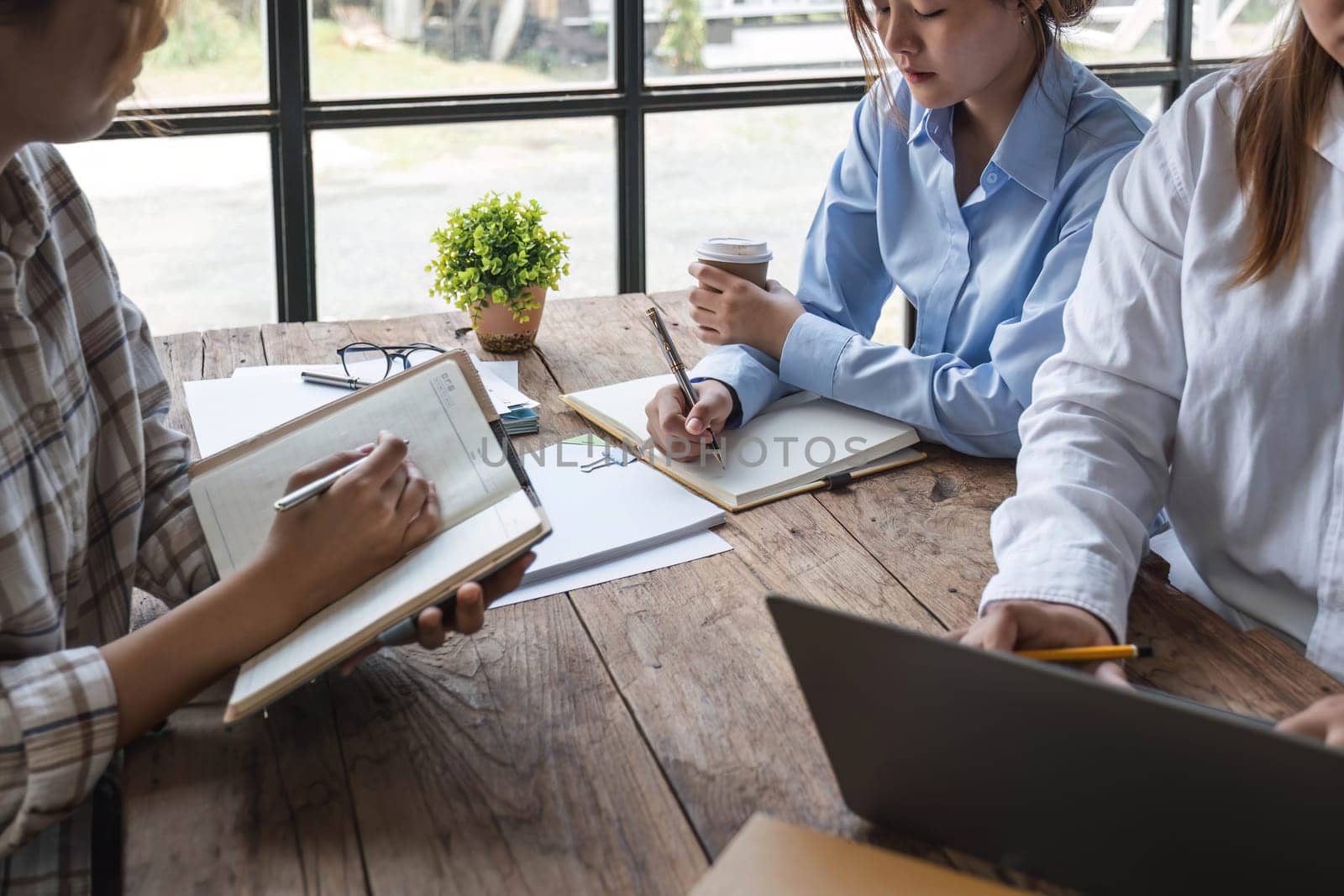 Asian College groups of students using laptop, tablet, studying together with notebooks documents paper for report near windows in classroom. Happy young study for school assignment, Soft focus by wichayada