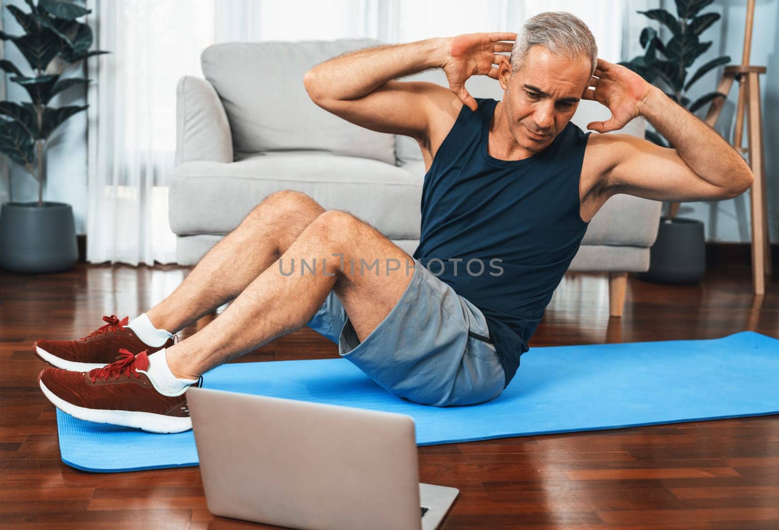 Athletic and sporty senior man doing crunch with online video. Clout by biancoblue