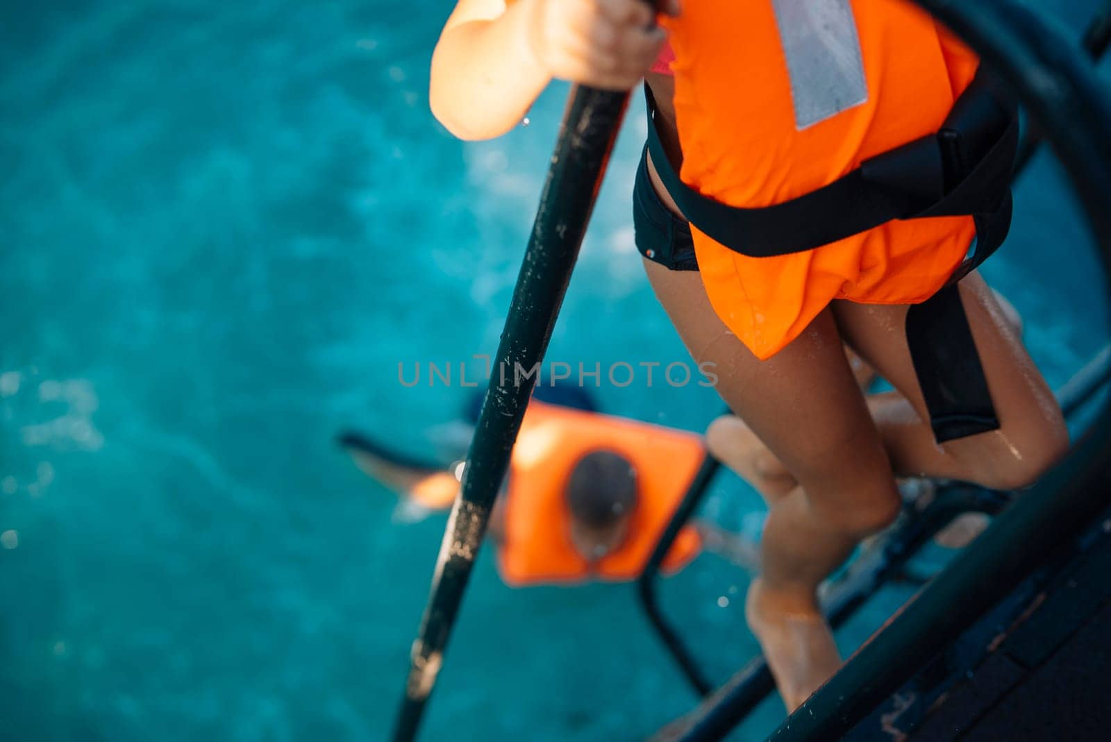 Children joyfully engaging in a fun water activity and climbing a colorful ladder while wearing vibrant life jackets