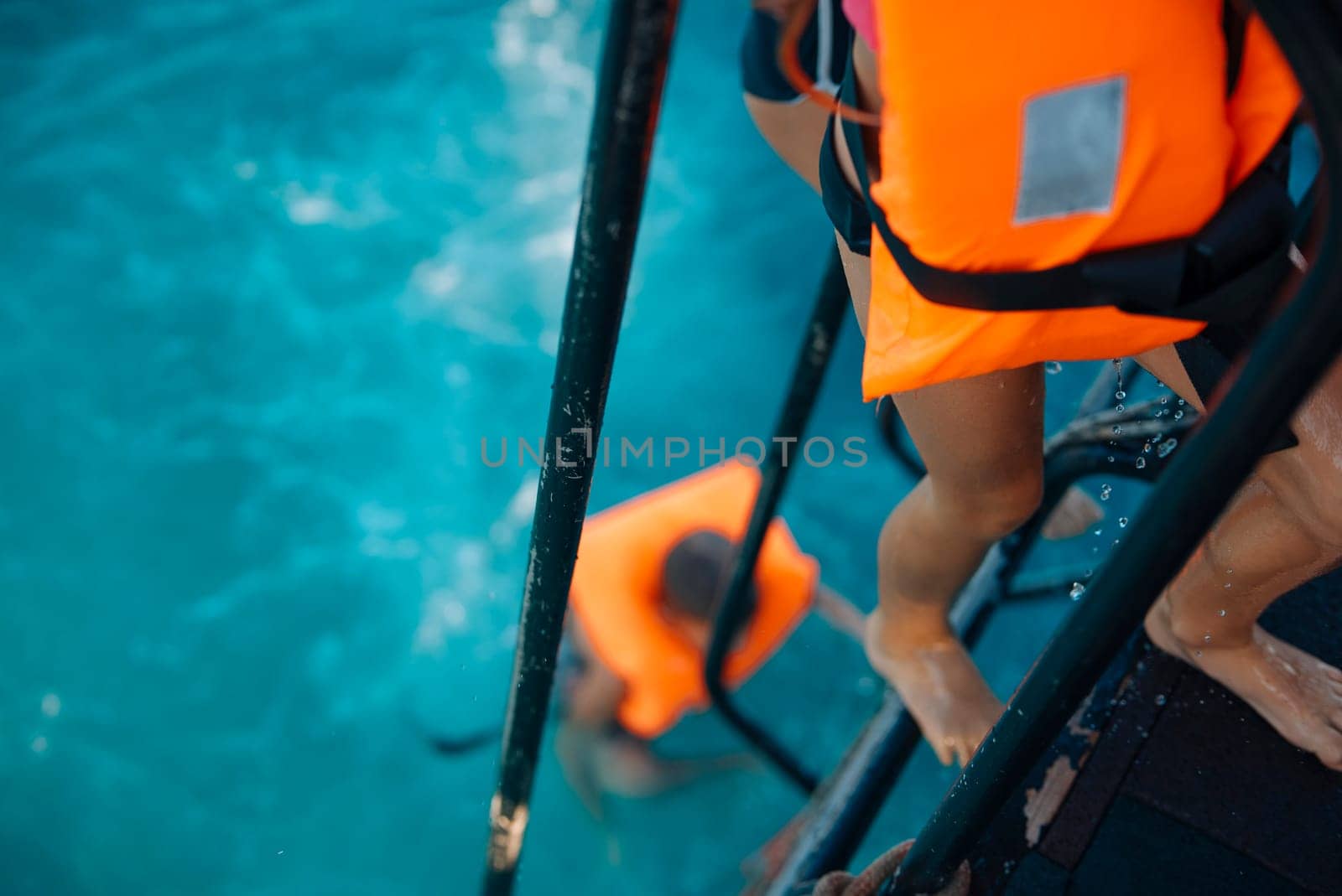 Children wearing bright life jackets are joyfully climbing into the water, embarking on fun and adventurous activities