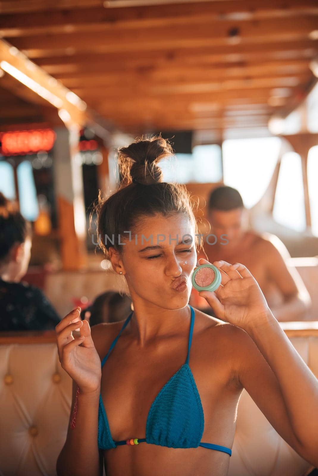 A playful young girl is having an enjoyable summer on a boat, wearing a vibrant bikini and exuding a relaxed mood