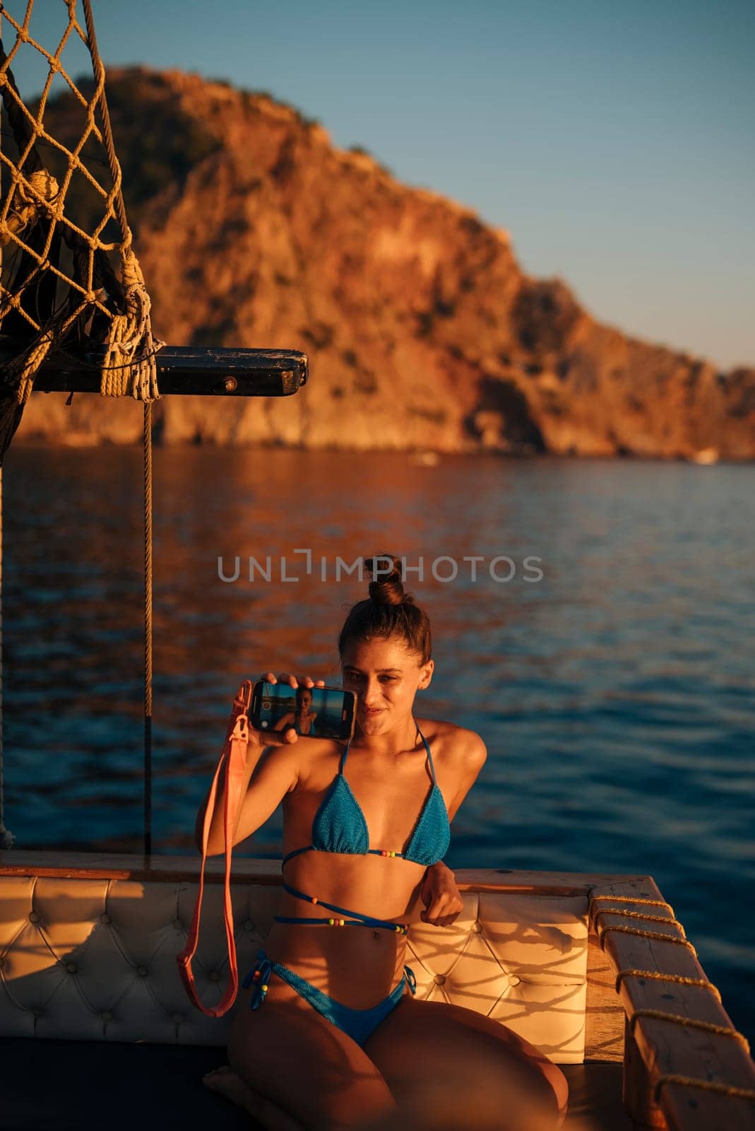 A serene summer scene showcases a woman in a stylish bikini capturing joyful memories as the sun gently sets