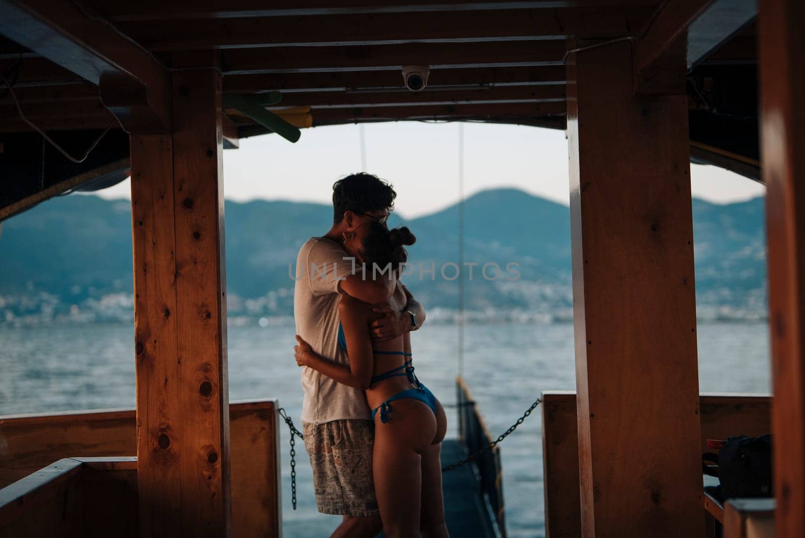 A couple embraces lovingly on a boat, enveloped by a breathtaking sunset that truly enchants the entire scene