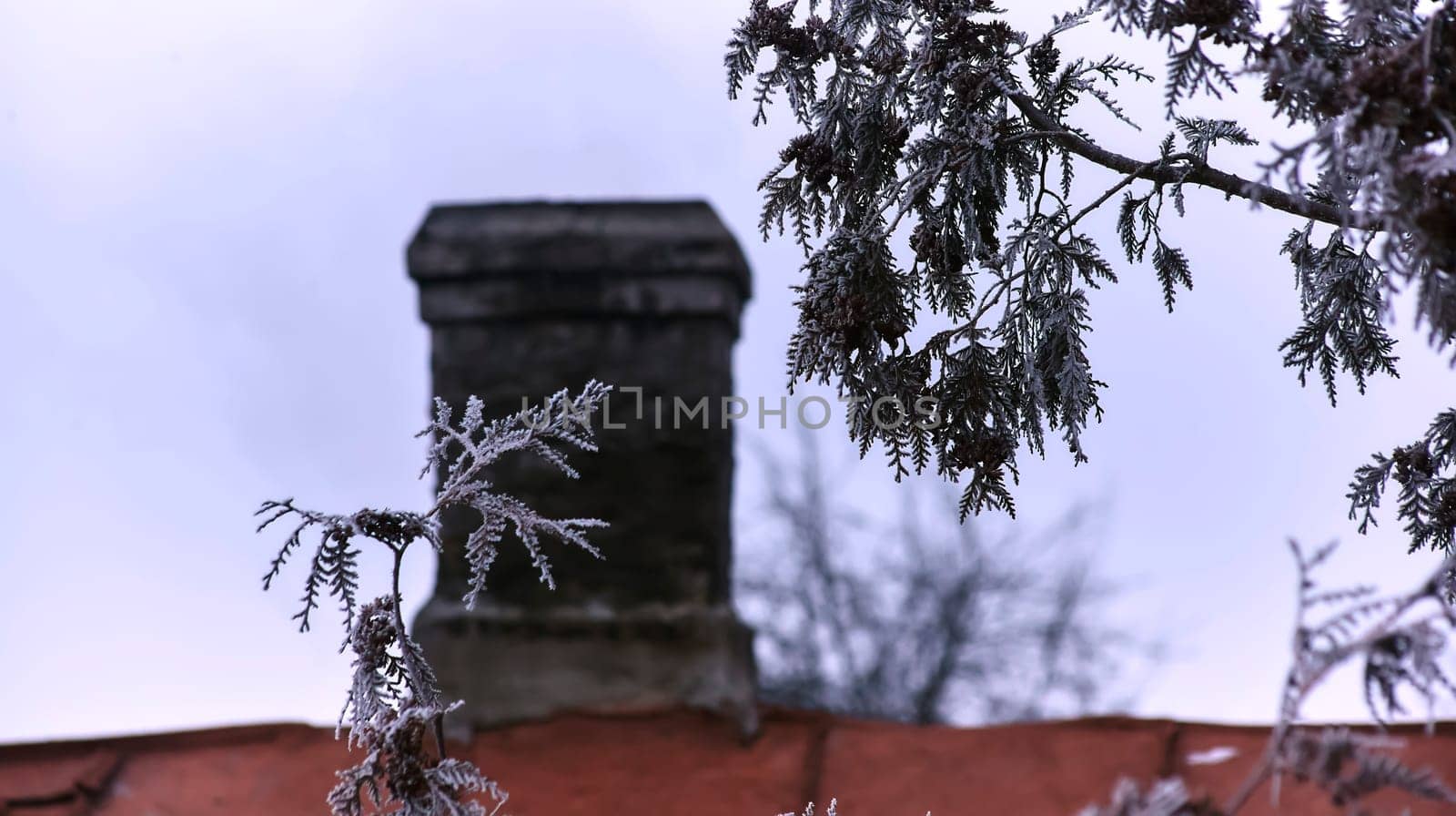 White smoke from the chimney of an old house during frost. Fireplace chimney on an iron roof.