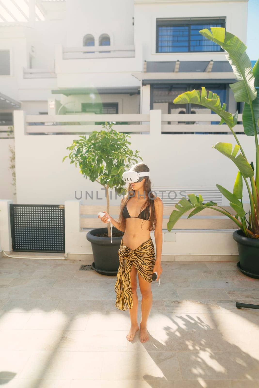 A woman dressed in a stylish beach outfit is enjoying the warm sun by a modern home, radiating summer elegance
