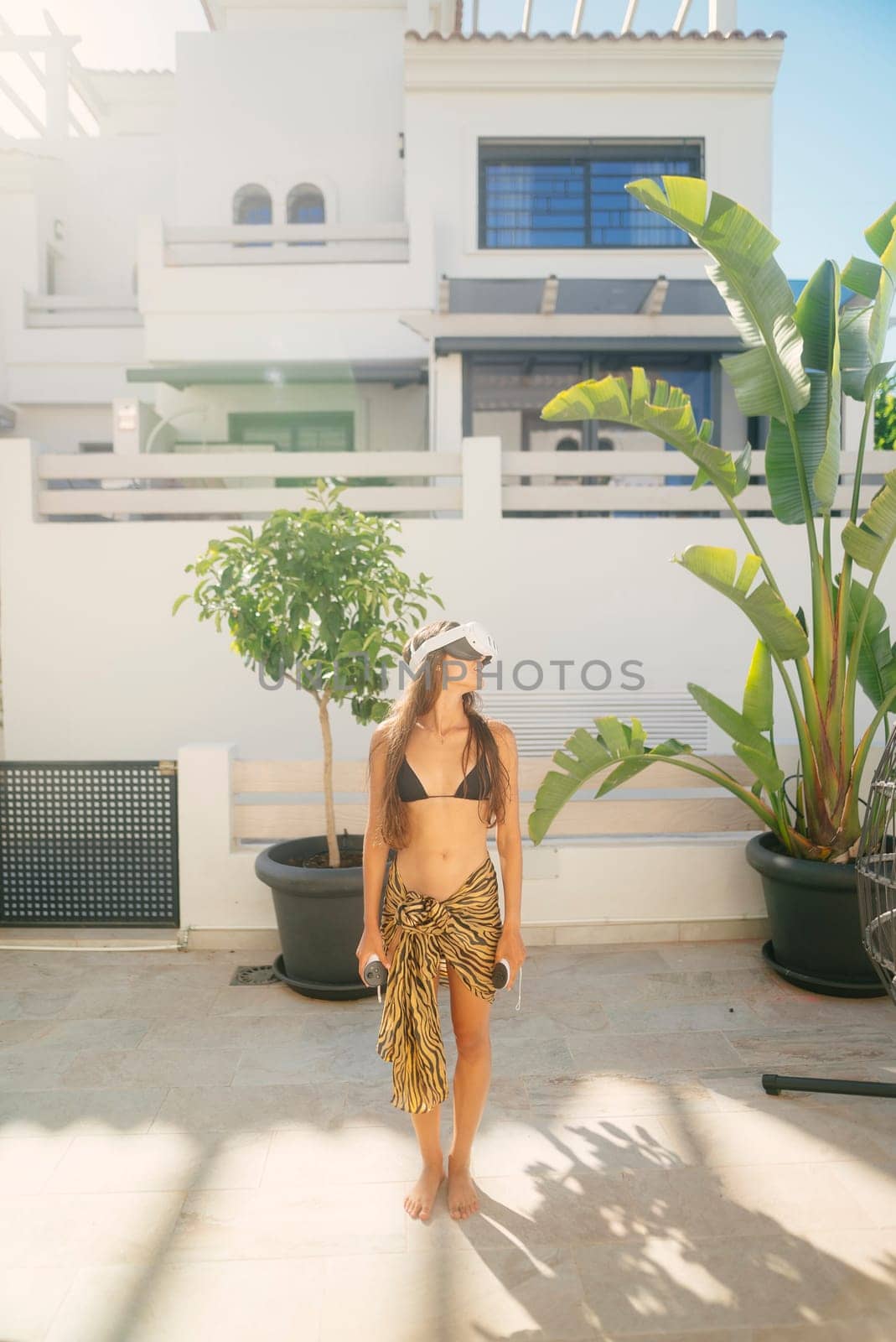 A stylish, fashionable woman revels in a bright, sunny day while enjoying a relaxed atmosphere in a tropical setting